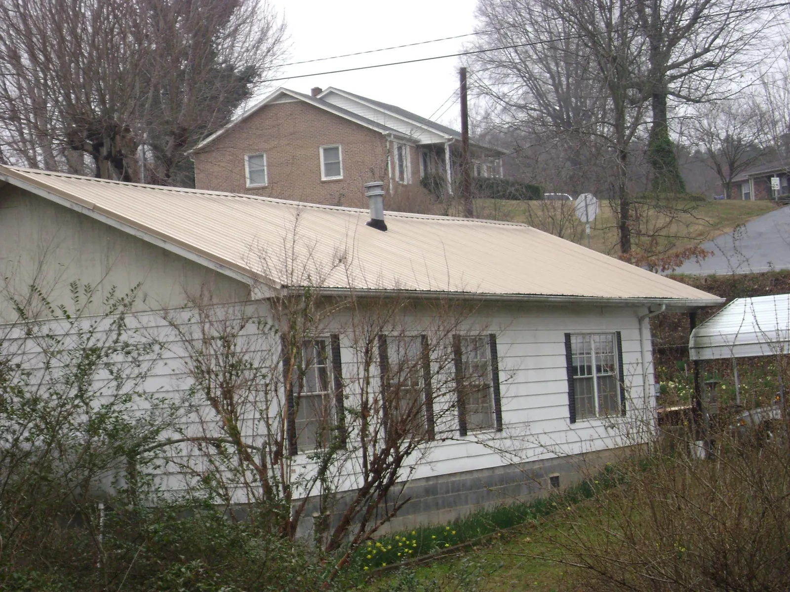 Tan metal roof on a white sided house set into a hillside — Commercial Roofing by Roofing Brothers in Ritzville