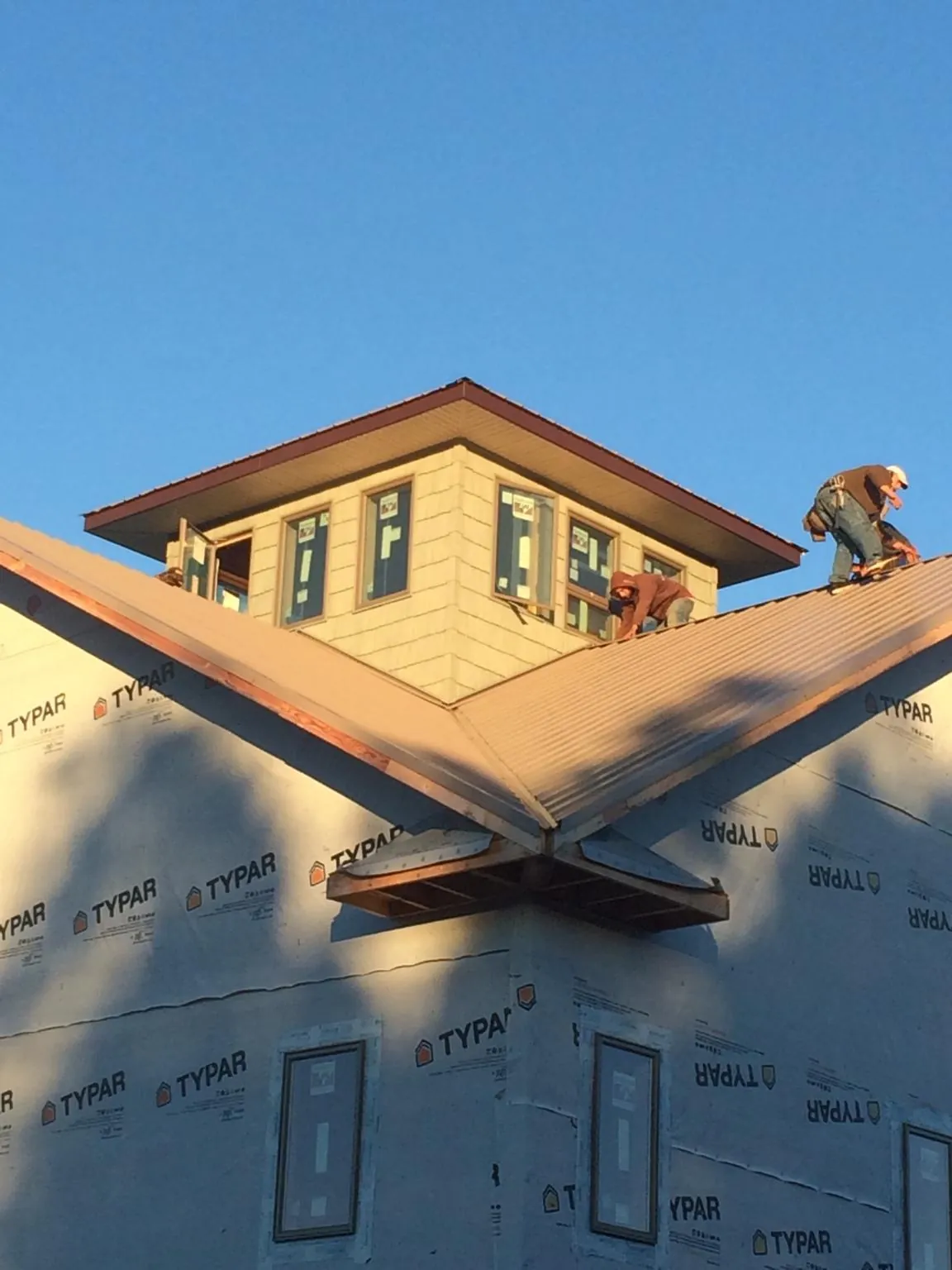 Roofers working around a rooftop cupola on a new metal roof at sunset — Roof Waterproofing in Ritzville by Roofing Brothers